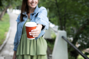 a young girl holding a glass of coffee at arm's length
