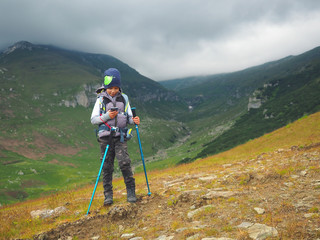 Obraz premium Little boy with backpack hiking in scenic mountains