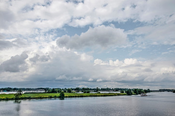 Dramatic clouds over the river Maas and the landscape beyond packed with lakes and marinas near Roermond, The Netherlands