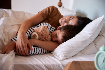 Mid adult woman sleeping in bed with her four year old son, waist up, close up