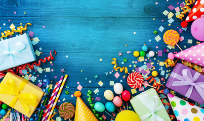 Gift or present boxes, holiday supplies and confetti on blue wooden table top view. Birthday party greeting card.