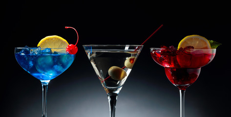 Two colorful cocktails and dry martini with green olives.