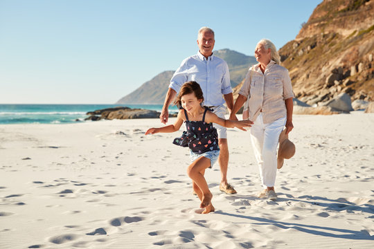 Senior white couple and their granddaughter walking on a sunny beach, close up
