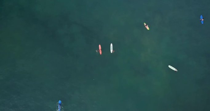 Cinematic aerial drone footage of sporty young surfer couple with long surf boards catch good wave in ocean. Modern active lifestyle. Water sport adventure camp. Extreme on summer vacation.