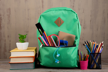 Education concept - school backpack with books and other supplies on the desk