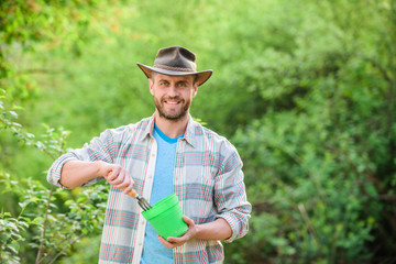 satisfied farmer hold garden rake and flower pot. muscular ranch man in cowboy hat. farming and agriculture. Garden tools. Eco farm worker. Harvest. happy earth day. Eco living. Flowers presentation