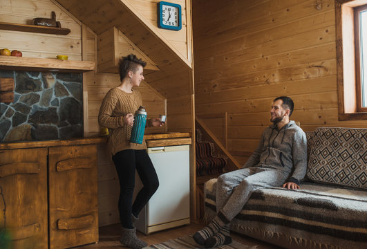 Hipster couple in traditional woollen sweaters and socks in the challet christmas decorated kitchen