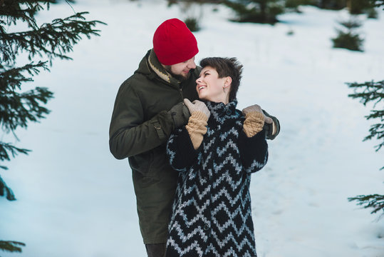 Happy hipster stylish couple play with snow in the forest