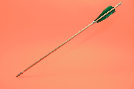 Old green wooden arrow on a beautiful peach background. - Powered by Adobe
