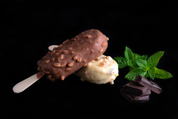 Frozen dessert,summer snack concept with close up of the popsicles on the black plate decorated with red currants,blackberries and mint.Ice cream covered of the hoarfrost.Isolated on black background.