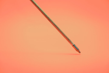 Old green wooden arrow on a beautiful peach background.