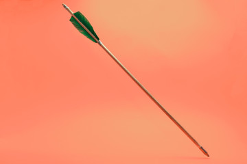 Old green wooden arrow on a beautiful peach background.