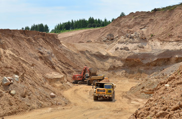 Excavator developing the sand on the opencast and loading it to the heavy dump truck. Processing of...