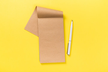 school notebook on a yellow background, spiral notepad on a table.