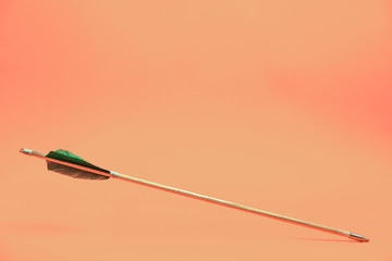 Old green wooden arrow on a beautiful peach background.