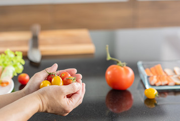 Holding fresh vegetable cherry tomato ingredient for cooking in modern kitchen background