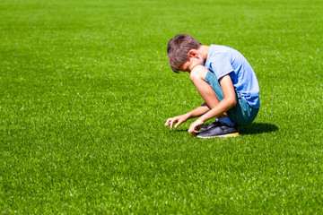 Fototapeta na wymiar Sad alone boy sitting on the grass outdoors