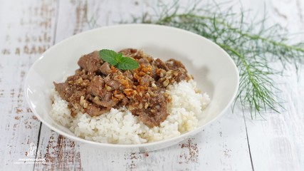 Stirred and fried pork with garlic and pepper served on steamed rice. Shooting in studio on backdrop for advertising. Thai and Asian food concept.