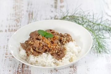 Stirred and fried pork with garlic and pepper served on steamed rice. Shooting in studio on backdrop for advertising. Thai and Asian food concept.