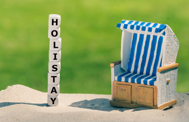 Holiday at home. Dice form the word "holistay" next to a beach chair.