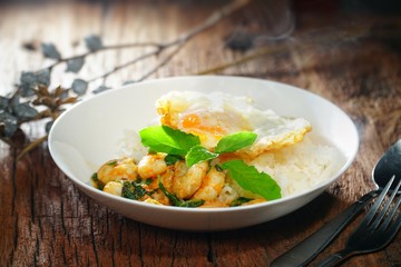 Thai food : Kaphrao Kung is Stirred and fried shrimps with holy basil and chilies served on steamed rice and fried egg. Shooting in studio for advertising. Thai and Asian food concept.
