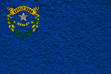 The national flag of the US state Nevada in against a gray wall with stony surface on the day of independence in colors of blue and yellow. Political and religious disputes, customs and delivery.