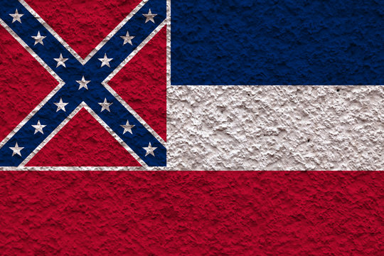 The national flag of the US state Mississippi in against a gray wall with stony surface on the day of independence in blue red and white. Political and religious disputes, customs and delivery.