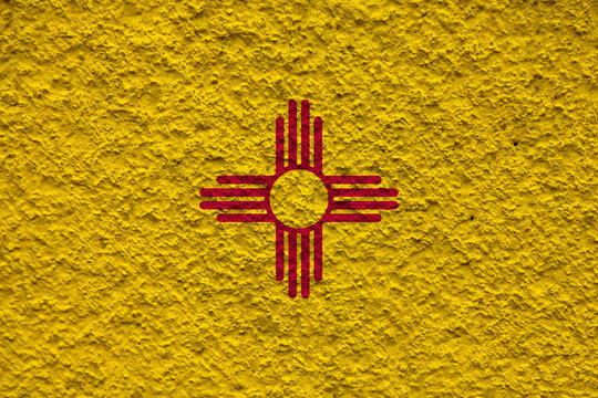 The national flag of the US state New Mexico in against a gray wall with stony surface on the day of independence in blue and yellow. Political and religious disputes, customs and delivery.