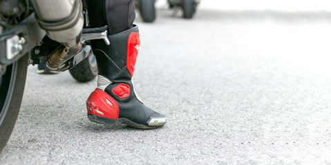 Plakat closeup leg of a motorcycle racer with with soft-focus and over light in the background