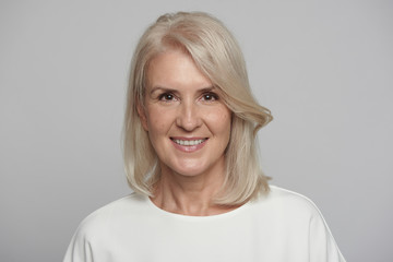 Portrait of beautiful senior woman in front of grey background