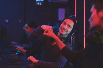 Team of computer gamers sitting at table and making fist bump while celebrating win in computer club © Seventyfour
