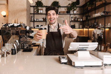 Handsome happy coffee man posing in cafe bar working indoors holding coffee cup.
