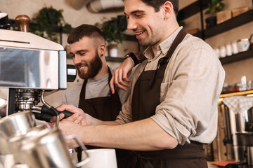 Group of cheerful men baristas wearing aprons