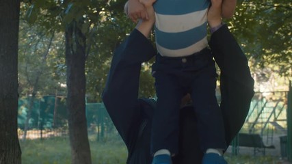 Mama putting a child on her shoulders. Mom with son on a walk. Parenthood concept