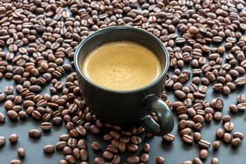 hot espresso and coffee bean on black table with soft-focus and over light in the background. top view