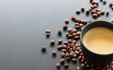hot espresso and coffee bean on black table with soft-focus and over light in the background. top view