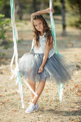 Girl swing. Children's fashion. Beautiful little girl in fashionable clothes. 