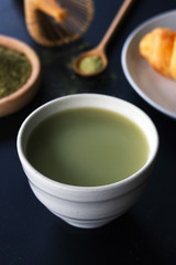 matcha green tea latte on black table with soft-focus and over light in the background