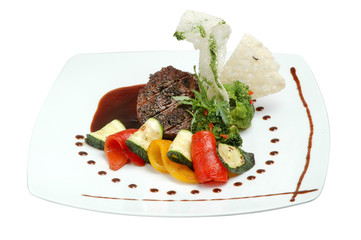 Steak with vegetables on a plate on a white isolated background