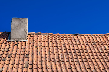 Traditional old Tile Roofing made of clay. Natural roofing material. Clay tiles with chimney on the background of blue sky.