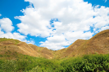 Erosion of land. Landscape with a picturesque ravine on a background of bright blue sky with clouds on a summer warm sunny day in nature outdoors