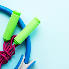 Sports background with Pilates ring, sports Mat, yoga, jump rope, water bottle on turquoise blue background with space for text.