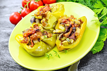 Pepper stuffed with vegetables in green plate on dark wooden board