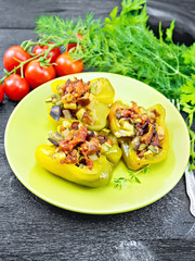 Pepper stuffed with vegetables in green plate on wooden board