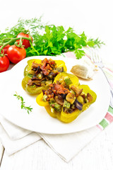Pepper stuffed with vegetables in plate on light wooden board