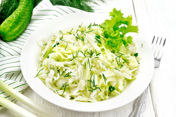 Salad of cabbage and cucumber in plate on white board