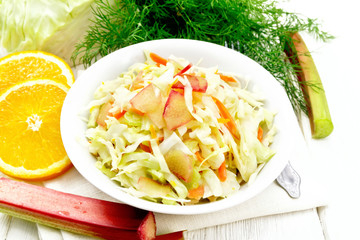 Salad of cabbage and rhubarb in plate on white wooden board