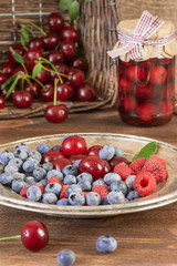 Ripe cherries, raspberries and blueberries on a wooden background