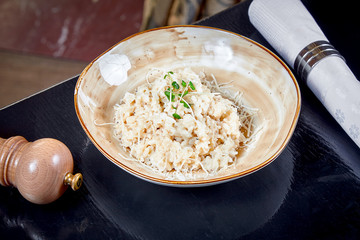 Close up view on Risotto with cheese parmesan in bowl. Lunch food. Italian cuisine. Dark background. Copy space. Horizontal restaurant food.