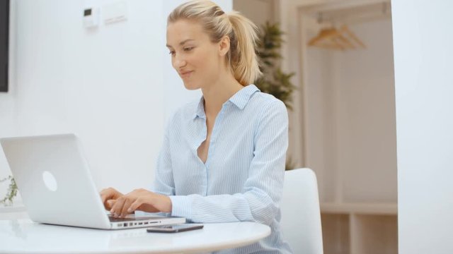 Young woman working on her laptop computer and using smartphone at home.